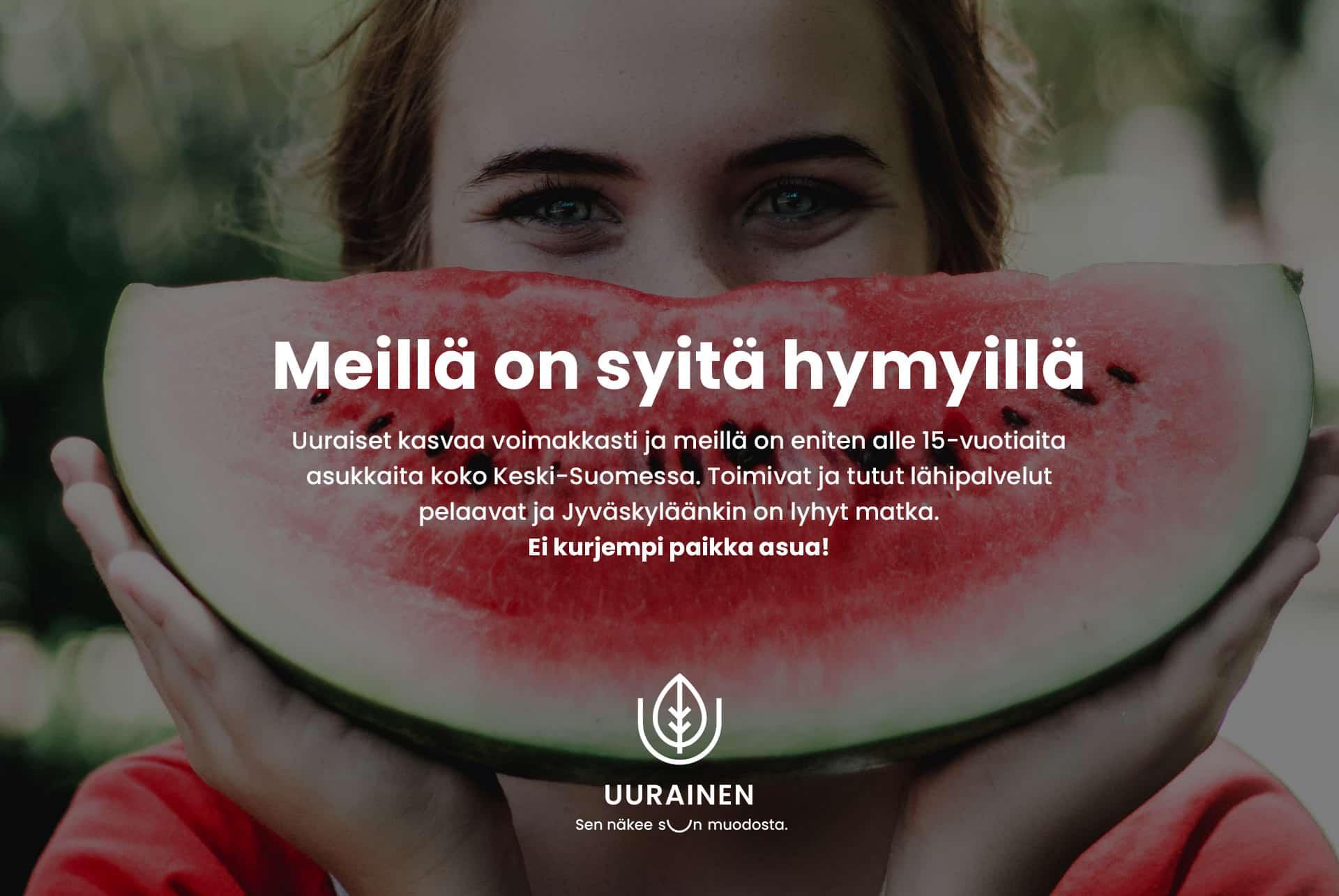Uuraisten kunnan mainos, jossa ihminen pitelee halkaistua vesimelonia kasvojensa edessä kuin hymyilevää suuta.